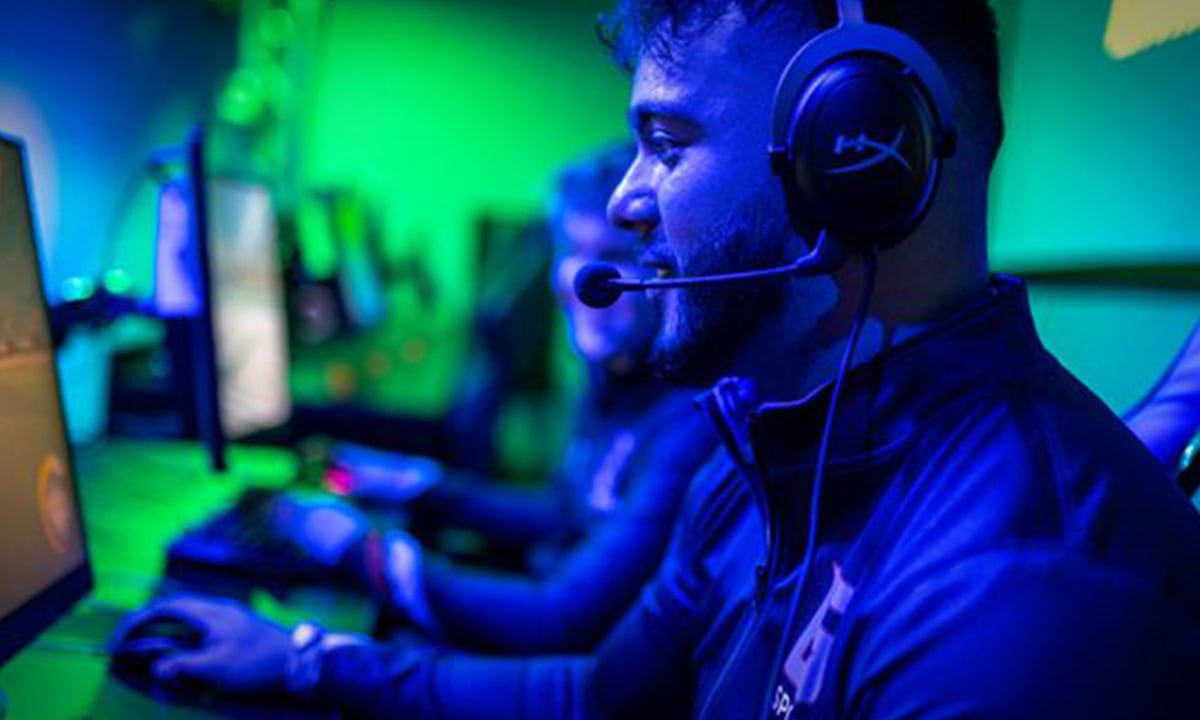 Professionele gamer met headset en monitor, klaar voor competitief gamen en e-sports, in een kleurrijke gamingruimte met LED-verlichting.