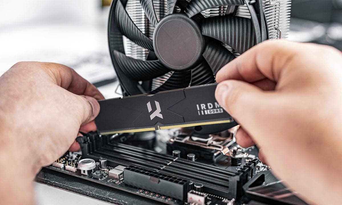 Close-up van een persoon die een IRDM 16GB DDR5 RAM-module installeert in een gaming PC, met een grote CPU-koeler op de achtergrond.