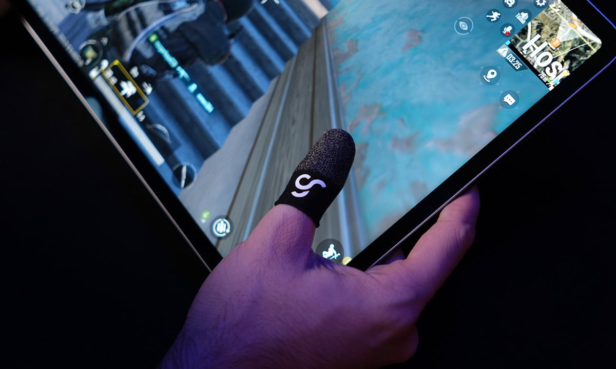 Close-up van een hand die een smartphone vasthoudt met een GameRaider mobiele gaming vingerhoes op de vinger, geschikt voor gaming onderweg.