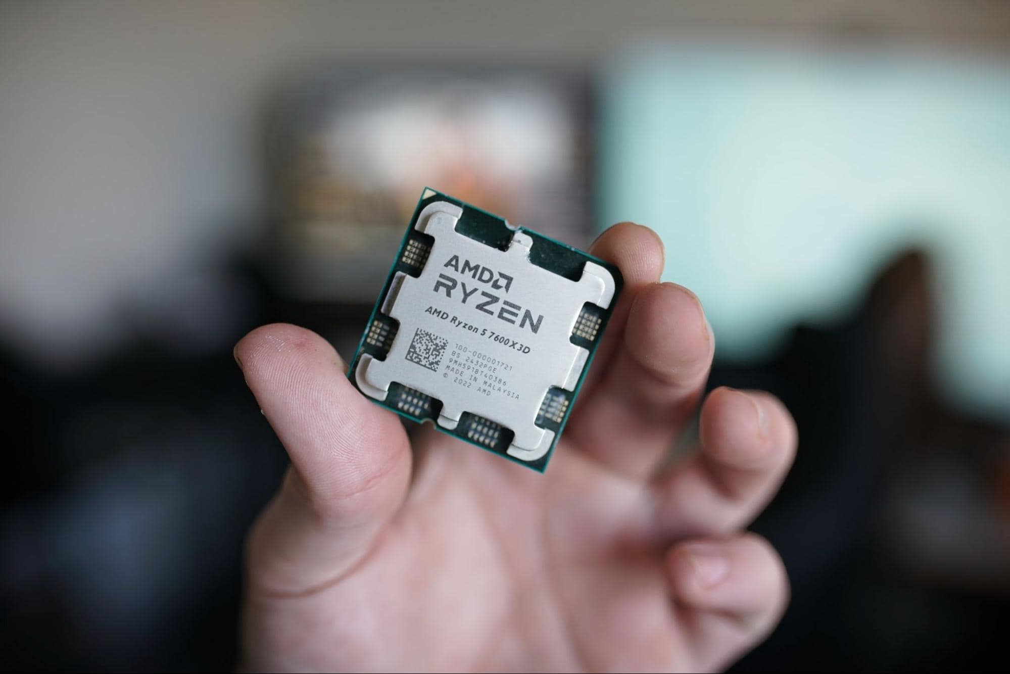 Hand holding an AMD Ryzen CPU processor, showcasing a high-performance computer component for gaming and professional use.