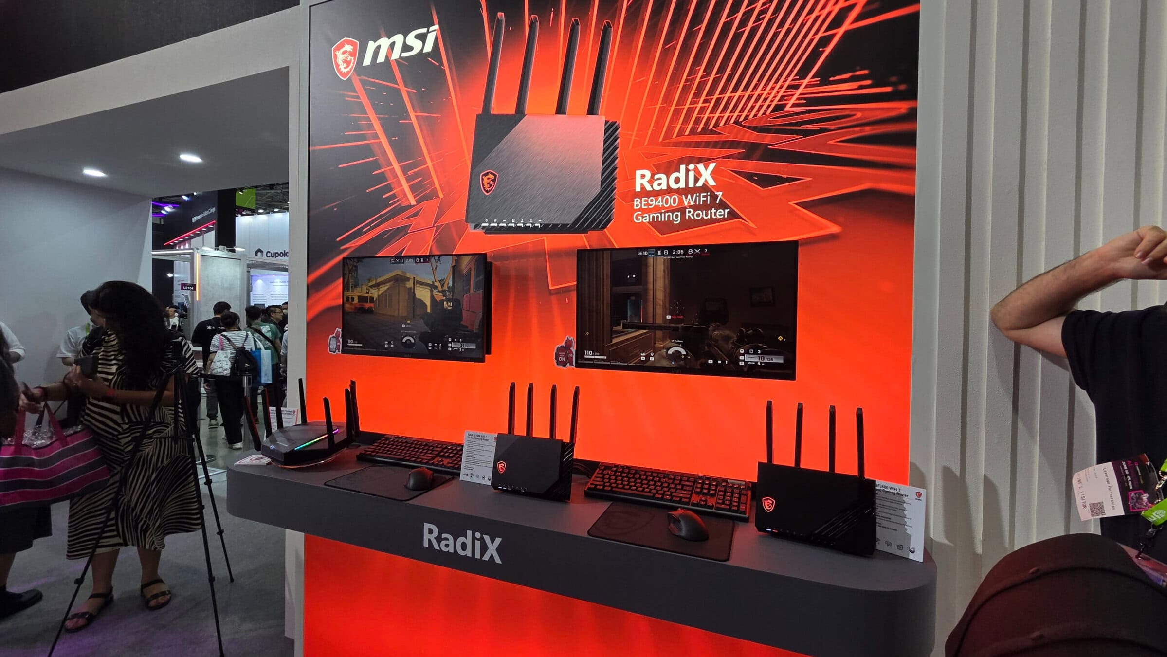 Radix Wi-Fi router en gaming accessoires op beursstand met ASUS en MSI branding, geschikt voor gaming en high-speed internet.